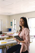 © Wavebreak Media - Young biracial female teacher stands confidently in a classroom in high school