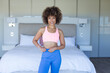 © Wavebreak Media - At home, biracial young female wearing sportswear standing in bedroom