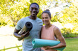 © Wavebreak Media - A diverse young couple holding yoga mats, smiling outside