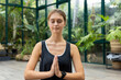 © Wavebreak Media - Glass house studio shows caucasian woman in black top meditating with eyes shut