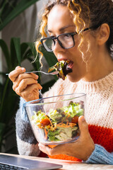 Young employee eating salads in fast lunch break while working on laptop without break. Busy businesswoman eating healthy and using laptop on the table. Office and business. Health lifestyle job