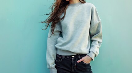 Female fitness model in a casual gray sweatshirt with black jeans, isolated on an aquamarine background
