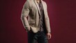 © Salman - Male fitness model in a smart casual outfit with a beige blazer and dark jeans, isolated on a burgundy background