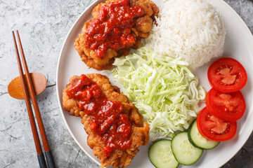 Wall Mural - Ayam geprek Crispy Chicken Smashed in Sambal served with white rice, cucumber, tomato and cabbage closeup on the plate on the table. Horizontal top view from above