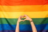 Hands showing heart and love against LGBT flag.