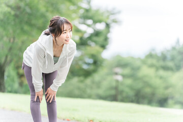 Canvas Print - 公園で準備体操・ストレッチするスポーツウェアのアジア人女性
