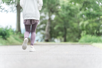 Canvas Print - ダイエット・カロリー消費のため公園でウォーキング・運動をするスポーツウェアのアジア人女性の足元
