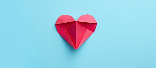 Wall Mural - Top view of a handmade pink paper heart in origami style set against a light blue background with copy space image.