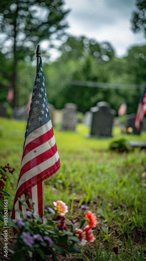 American flag on a grave in a cemetery, surrounded by flowers and ...