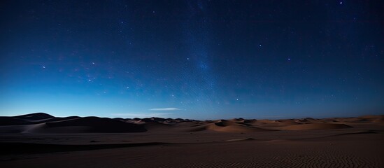Wall Mural - nightly desert hills and dunes under a starry sky with clouds in blue hues, ideal for a photo with c