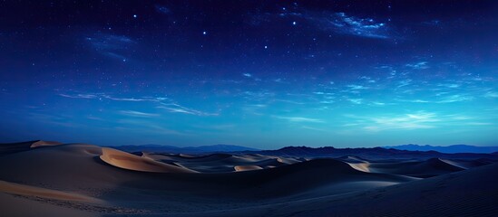 Wall Mural - nightly desert hills and dunes under a starry sky with clouds in blue hues, ideal for a photo with c