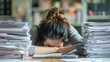 © Saha165 - Exhausted office worker with head on desk, surrounded by piles of paperwork