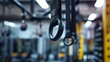 © anza - A suspension trainer's handles hanging from a gym ceiling, focus on the texture and material, with a softly blurred background of gym equipment.