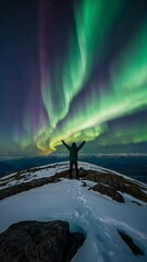 Wall Mural - A lone person stands on top of a big mountain with hands towards the sky as to celebrate their achievement