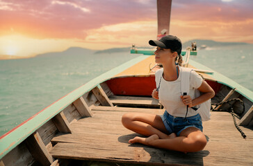 Wall Mural - Happy vacation in Thailand. Young woman sailing the sea on traditional longtail boat.