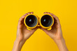 © Dima - Female hands holding binoculars on a yellow background, representing exploration and curiosity concept. Generative AI