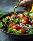 Hand pouring golden olive oil over a vibrant bowl of mixed salad with tomatoes and onions in a closeup shot