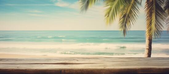 Poster - Blur tropical beach with bokeh sun light wave and palm tree on copy space empty old wood table abstract background Product presentation in nature Vintage tone filter effect color style