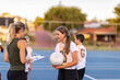 © Austockphoto - female netball coach with a girl holding a netball on an outdoor netball court