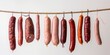 © Iryna - A variety of sausages hang on a white background.