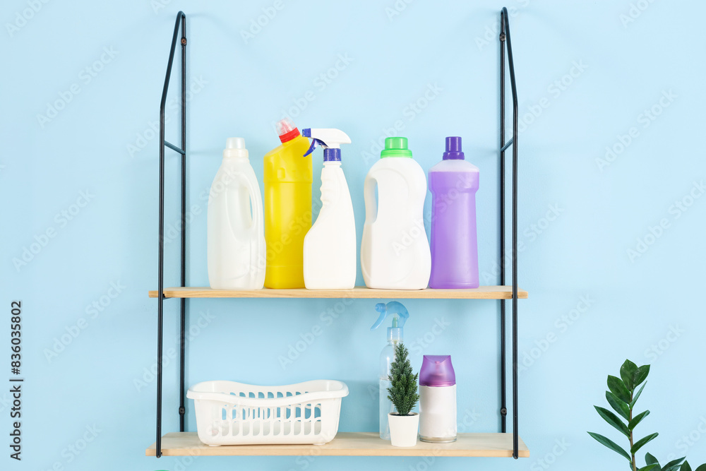 Shelf with bottles of laundry detergent hanging on blue wall, closeup