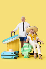 Wall Mural - Mature business people with Mexican pinata and suitcases ready for summer vacation on yellow background