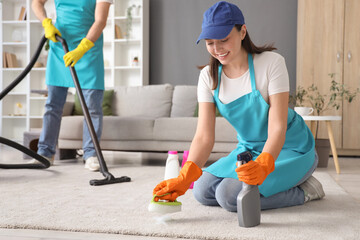 Wall Mural - Female janitor cleaning carpet with brush in room