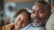 © familymedia - An endearing shot of an African American grandfather and his granddaughter resting together, showcasing a bond across generations