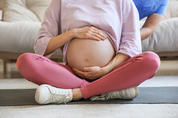 Sticker - Young pregnant woman with doula sitting on mat at home, closeup