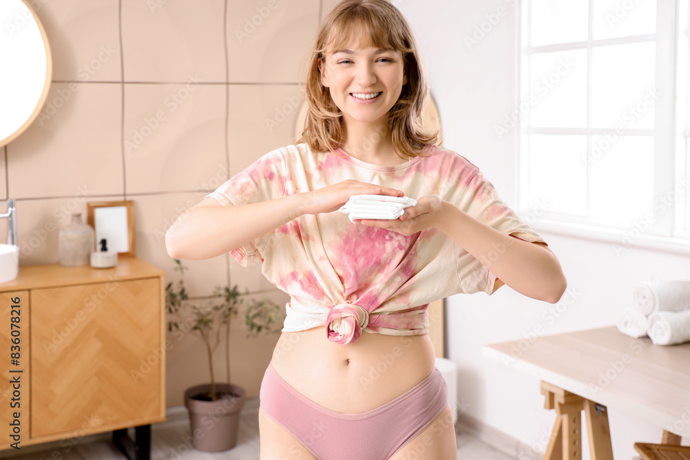 Young woman with menstrual pads in bathroom