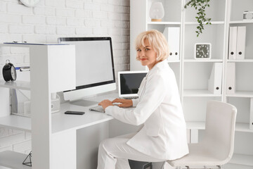 Wall Mural - Mature businesswoman working with computer at table in office