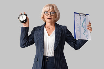 Sticker - Stressed mature businesswoman with alarm clock and clipboard on light background