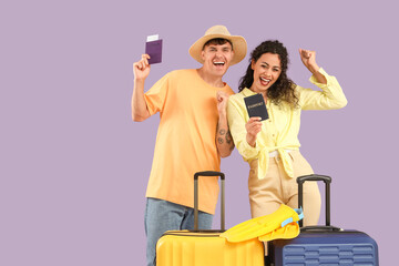 Wall Mural - Happy young couple with suitcases and passports on lilac background