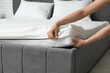 © Pixel-Shot - Woman with soft orthopedic mattress making bed at home, closeup