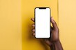 © Adam - African American hand holding smart phone with empty screen with copy space, isolated on a yellow background