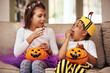 © peopleimages.com - Halloween, eating sweets and kids in home with costume for holiday event, celebration and siblings with pumpkin. Couch, young girl and boy with orange vegetable for candy, smile and fairy outfit