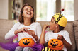 © peopleimages.com - Halloween, eating candy and kids in home with costume for holiday event, celebration and happiness with pumpkin. Couch, young girl and boy with orange vegetable for sweets, smile and fairy outfit