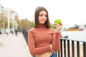 teenager girl with an apple at outdoors with sad expression