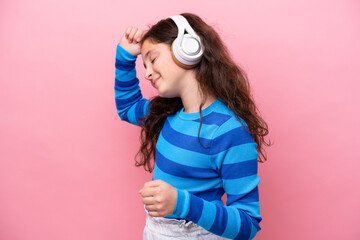 Wall Mural - Little girl isolated on pink background listening music and dancing