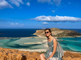 Poster - Woman sits on mountain edge, gazes at beach below