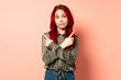 © luismolinero - Teenager red hair girl isolated on pink background pointing to the laterals having doubts