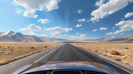A lone car traverses a long, winding desert highway, dwarfed by the vast, dramatic landscape and endless horizon. A bright day adds warmth and vibrance to this scene.