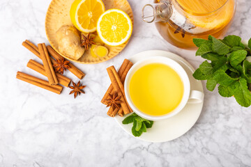 Wall Mural - Fragrant hot tea with cinnamon stick and anise on a textured wooden background. A cup of hot tea with honey, lemon, mint and apples. Spicy tea with spices. Immunity tea. Health concept.Copy space.