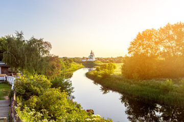 Summer landscape in Suzdal. Church of Elijah the Prophet on the bank of the river Kamenka. Tourists on SUP boards float on the river. Russia, Vladimir region, Golden Ring of Russia