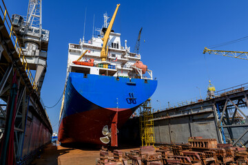 Cargo vessel in dry dock on ship repairing yard. Variable pitch propeller and rudder.