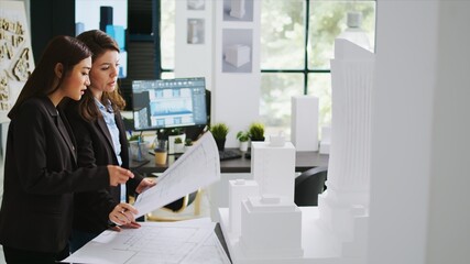 Architects team studying 3d printed building model in office, looking at scale and outline to reveal floor plan measurements. Creative agency employees working with architectural blueprints.