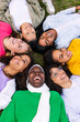 © Xavier Lorenzo - Vertical photo. High angle view of diverse happy group of young girls lying on grass at park. Female friendship and empowerment concept.