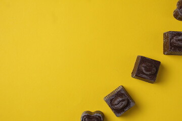 Wall Mural - Chocolates lie in a row top view on a yellow background with space for copy space text