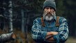 © Khoirul - Close up of lumberjack man wearing blue shirt and beanie hat in the middle of the forest cross arms pose. Tree logging handyman carpenter.