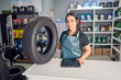 © oscargutzo - Young Latina saleswoman holding a tire at the counter in a small auto parts supply business